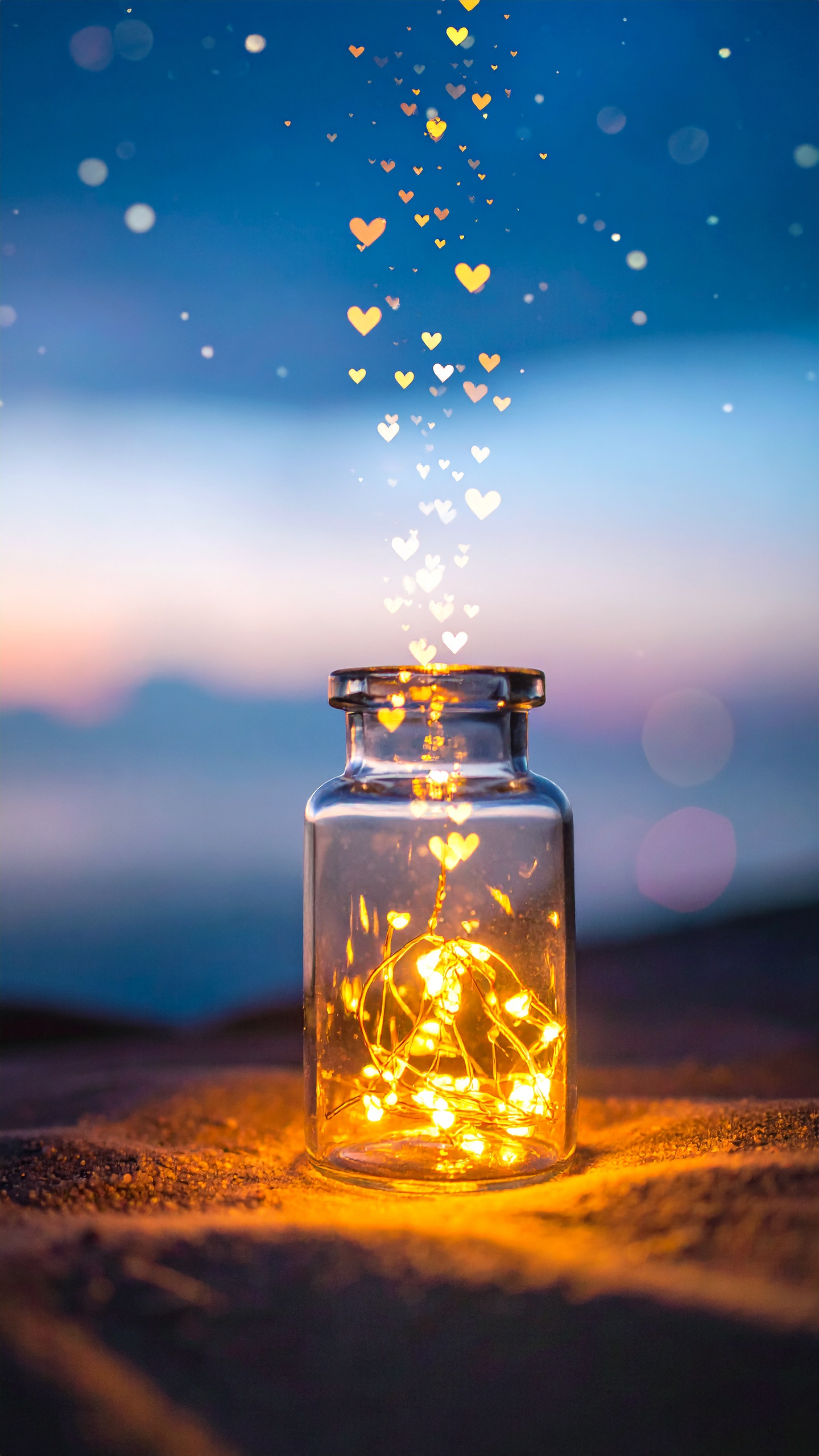夜の砂浜に静かに佇む、光輝くガラス瓶。瓶の中に閉じ込められた黄金色のライトが、小さなハートの形となって夜空へ優しく舞い上がる幻想的なデザインです。