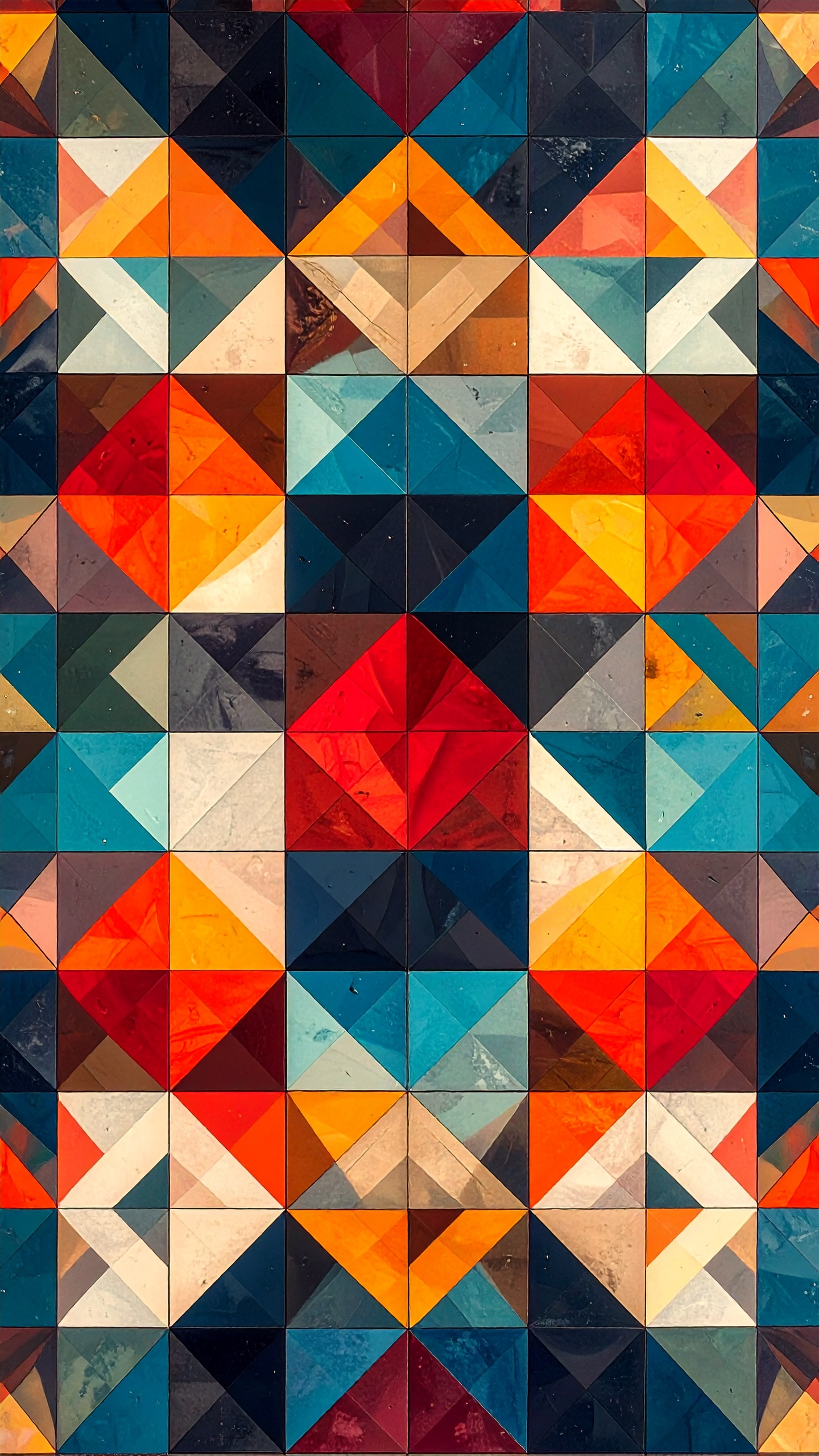 赤、青、オレンジなどの強い色彩で構成された、三角形のタイルが並ぶ幾何学模様。